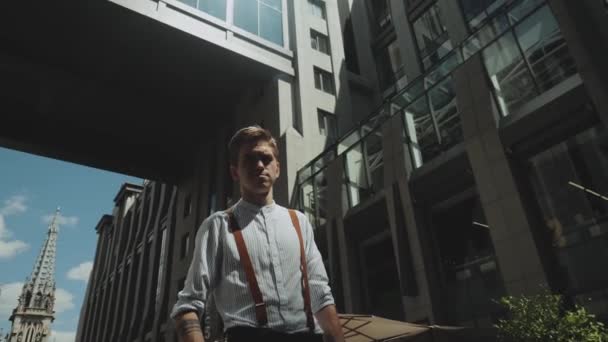 Mann blickt in die Kamera, während er im Hintergrund vor einem Geschäftshaus steht. Medium shot Portrait einer männlichen Person in stilvoller Kleidung . — Stockvideo