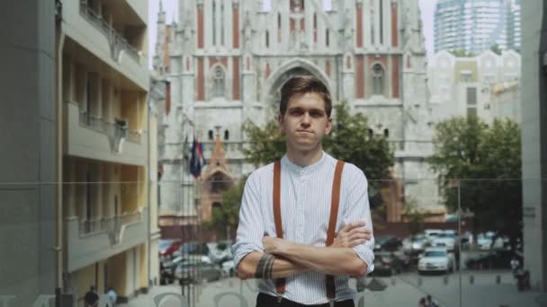 Medium shot Portrait einer männlichen Person in stilvoller Kleidung. Mann blickt in Kamera, während er im Hintergrund vor Geschäftshaus steht. — Stockvideo