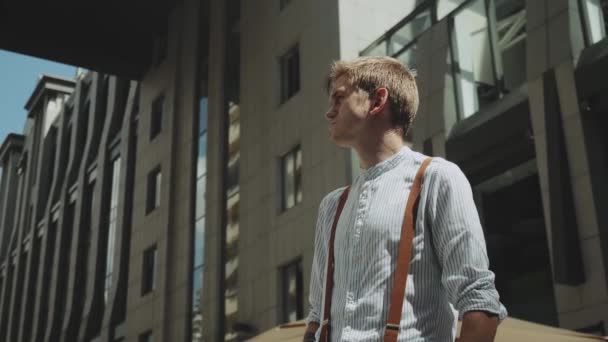 Im Hintergrund steht ein Mann vor einem Geschäftshaus. Medium shot Portrait einer männlichen Person in stilvoller Kleidung . — Stockvideo