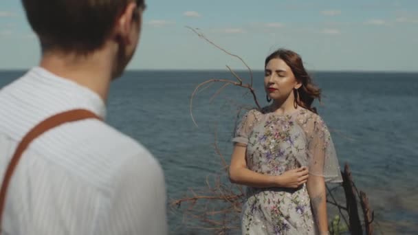 Närbild av glada kärleksfulla par står framför varandra på avstånd havet på bakgrunden. kärlek, relation och umgänge. — Stockvideo