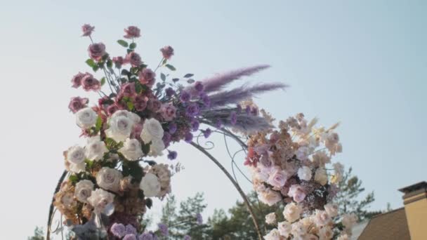 Medium shot view of Wedding floral decorations of flowers in pastel faded colors slow motion, outside wedding ceremony in park, the suns rays shine through the arch. — Vídeos de Stock