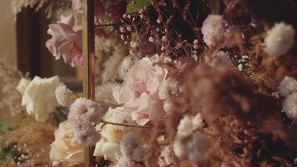Вид крупним планом Весільні квіткові прикраси з квітів в пастельних зів'ялих кольорах повільний рух, зовні весільна церемонія в парку, промені сонця світяться через арку . — стокове відео