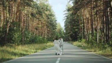 Neşeli genç Avrupalı bir çift, çam ormanında yumuşak doğal ışıklandırmayla pitoresk bir yerde yürüyor. Çift öpüşüyor, sarılıyor, el ele tutuşuyor, çift öpüşüyor ve sarılıyor. yavaş çekim 