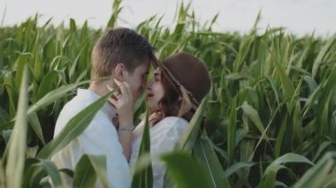 Loving couple in the corn field. slow motion. Couple hugging and kissing farmland medium shot . Caucasian man holding girls face in his arms closed eyes. Couple, date, love and lifestyle concept.