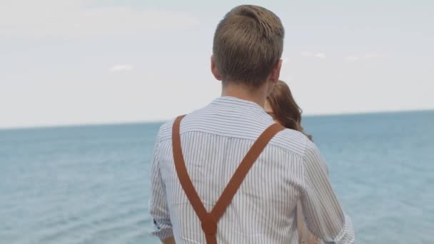 The guy comes up to the girl, hugs and strokes her hair, the girl smiles at him slow motion. Close-up of couple in love hugs, the sea is in the background. — Stok video