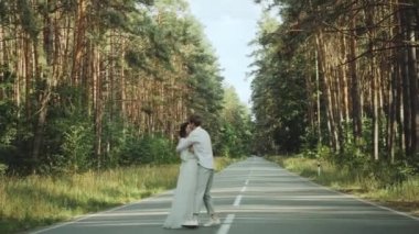 Aşık hippi çift güzel bir yerde yürür, el ele tutuşur, kadın ve erkek, boş yolda pikoresk çam ormanlarında sarılır ve eğlenir. yavaş çekim 