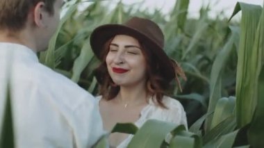 Mısır tarlasında birbirini seven bir çift. Ağır çekim. Kahverengi şapkalı genç bir kadının, erkek arkadaşını mısır tarlasında çekerken beni takip edin.. 