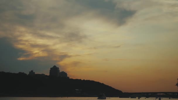 Вид на місто Київ з річки Дніпро в сутінках. сутінки над містом Київ сповільнюють рух. — стокове відео