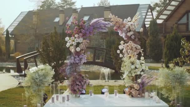 Vista de la boda decoraciones florales de flores en colores pastel descoloridos cámara lenta, fuera de la ceremonia de boda en el parque, los rayos del sol brillan a través del arco. — Vídeos de Stock