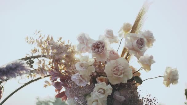 Nahaufnahme der Hochzeit Blumenschmuck Bogen von Blumen in pastellfarbenen verblassten Farben Zeitlupe, außerhalb Trauung im Park, die Sonnenstrahlen scheinen durch den Bogen. — Stockvideo