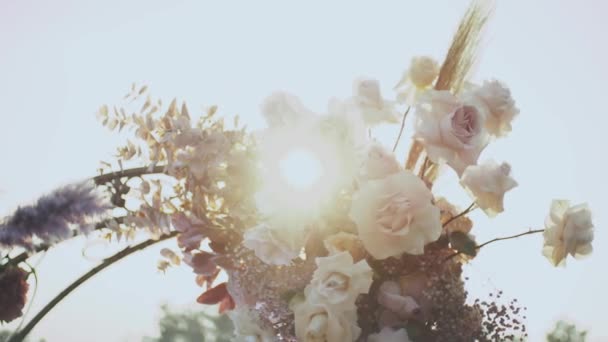 Nahaufnahme der Hochzeit Blumenschmuck Bogen von Blumen in pastellfarbenen verblassten Farben Zeitlupe, außerhalb Trauung im Park, die Sonnenstrahlen scheinen durch den Bogen. — Stockvideo
