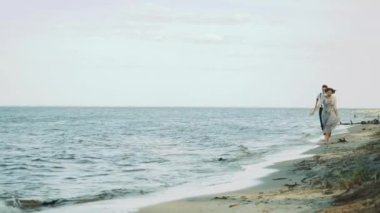 Sahilde birlikte koşan mutlu çift harika ve çok romantik hissediyorlar, el ele tutuşuyorlar ve ayakları suyun üzerinde yürüyorlar. Yüksek kalite 4k görüntü