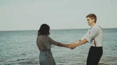 Mutlu çift tatilde deniz kenarında el kamerasıyla fotoğraf çekerken eğleniyor. Doğanın ufuk çizgisinde sevgi gösteren gençler. Çekici kız arkadaşın dönüyor. Boş zaman konsepti. 4k