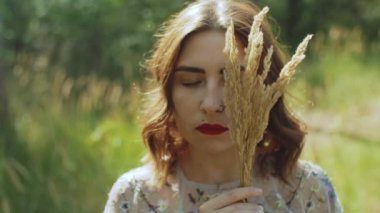 Çekici bir kadının portresi. Gözleri kapalı ve elinde yüzüne yakın bir buket çivi var. Yüksek kalite 4k görüntü