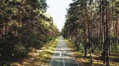 Neşeli genç Avrupalı bir çift, çam ormanlarının hava manzarasında, yumuşak doğal ışıklandırmayla pitoresk bir yerde yürüyor. Çift öpüşüyor, sarılıyor, el ele tutuşuyor, çift öpüşüyor ve sarılıyor. 4k