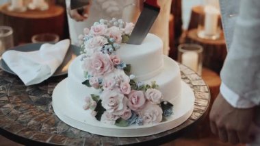Yeni evlilerin düğün pastasının ayrıntıları. Çiçeklerle süslenmiş düğün pastası, pastel pembe güller yavaş çekim. Yüksek kaliteli FullHD görüntüler