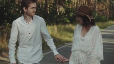 Neşeli genç Avrupalı bir çift, çam ormanında yumuşak doğal ışıklandırmayla pitoresk bir yerde yürüyor. 4K atışı. Yüksek kalite 4k görüntü