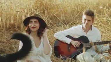 Aşık bir çift dikenli çengeller alanında köpekle oynuyorlar. Genç bir çifti tarlada vurmuşlar. Gitarcı kızı dinliyorlarmış. Yüksek kalite 4k görüntü