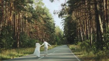 Neşeli genç Avrupalı bir çift, çam ormanında yumuşak doğal ışıklandırmayla pitoresk bir yerde yürüyor. 4K atışı. Yüksek kalite 4k görüntü yavaş çekim