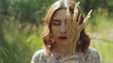 Çekici bir kadının yakın plan portresi. Gözleri kapalı ve elinde bir buket dikenle yüzüne yakın, yavaş çekim. Yüksek kalite 4K görüntü.