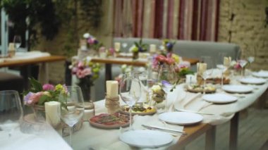 Güzel bir düğün dekoru, pembe pastel renklerle süslenmiş, kamera ağır çekimde hareket ediyor. Masada servis edilen şenlik tabakları. Yüksek kaliteli FullHD görüntüler