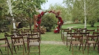Parktaki ağır çekimde kırmızı kemer ve tahta sandalyeler. Boho-şık düğün tarzı. Yüksek kaliteli FullHD görüntüler
