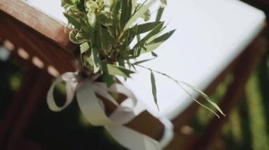Çiçeklerin rengarenk düğün süslemelerine yakından bakınca solgun renkler yavaş çekimde görünüyor. Çiçeklerle süslenmiş tahta sandalyeler. Dışarıdaki düğün töreninin çerçevesi parkta. Yüksek kaliteli FullHD görüntüler