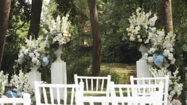 Μεσαία Καμάρα Γάμου Διακοσμημένη Παστέλ Ξεθωριασμένα Λουλούδια Και Λευκές Καρέκλες — Αρχείο Βίντεο