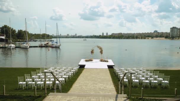 Weeding Arch Decorated Pastel Faded Flowers White Chairs Lake Background — 비디오