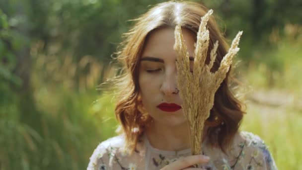 目を閉じた魅力的な女性と 顔の近くに彼女の手の中にスパイクの花束のクローズアップ肖像画 スローモーションショット 高品質4K映像 — ストック動画