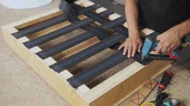 Bir işçi mobilya fabrikasında bir kanepe yapar. Erkek eli, kanepenin bir parçasını yapıyor. Yavaş çekim. Yüksek kalite 4k görüntü