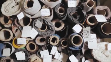 Rolls of fabric and textiles for sale stacked on shelves in shop. Warehouse various fabric, slow motion. High quality 4k footage