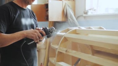 A professional carpenter working with wood on a woodworking machine grinds and polishes wood. Handmade furniture. Manufactures furniture parts in natural light. Slow motion. Carpentry tools.4k