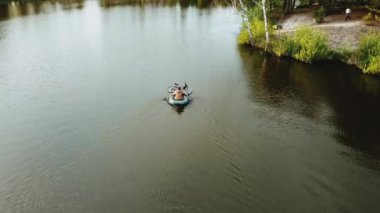 Aerial view of small island with pine trees in the middle of the lake.Unrecognizable people in a boat in the middle of the lake. Close-up shot of island. High quality 4k footage