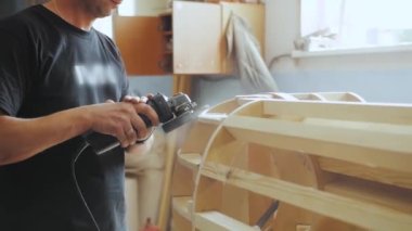 A professional carpenter working with wood on a woodworking machine grinds and polishes wood. Handmade furniture. Manufactures furniture parts in natural light. Slow motion. Carpentry tools.4k