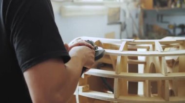 A professional carpenter working with wood on a woodworking machine grinds and polishes wood. Handmade furniture. Manufactures furniture parts in natural light. Slow motion. Carpentry tools.4k
