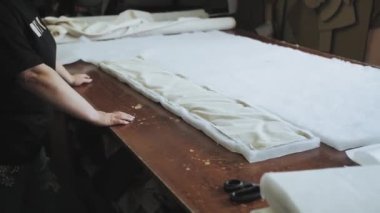 Yakın çekim kadın elleri, mobilya fabrikasında bir kanepe yapımı için kesilmiş köpük kauçuk katlar, yavaş çekim. Yüksek kalite 4k görüntü 