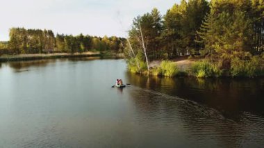 Aerial view of small island with pine trees in the middle of the lake.Unrecognizable people in a boat in the middle of the lake. Close-up shot of island. High quality 4k footage