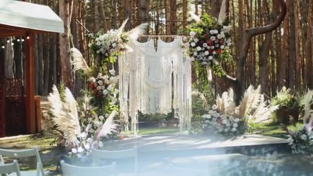 パステルカラーの花の結婚式のアーチの装飾は ゆっくりと動き 松と公園での結婚式の外に 太陽の光はアーチを通して輝きます フルHd映像 — ストック動画
