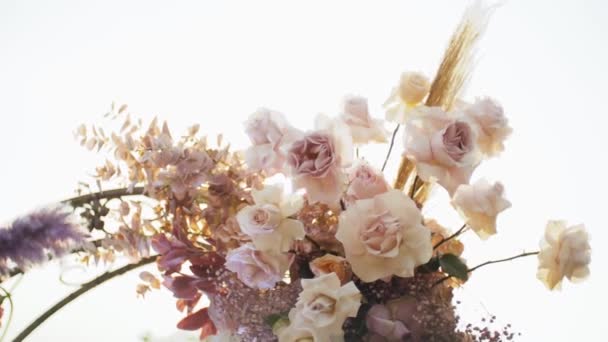 特写的婚礼花卉装饰拱形花被漆成淡淡的颜色 外面的婚礼仪式在公园里 阳光透过拱门闪耀 Fullhd视频 — 图库视频影像