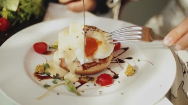 女人在餐馆吃美味的早餐 只有手拿叉子 女人拿着叉子 在瓷盘上品尝煮过的鸡蛋 — 图库视频影像