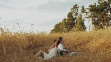 Aşık bir çift çivili kazık tarlasında köpekle oynuyorlar. Sahada genç ve sevgi dolu bir çift, gitar çalan kızı dinleyen bir adam. Yüksek kalite 4k görüntü