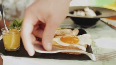 Yazlık kafede Benedict yumurtası, Amerikan kahvaltısı çatallı insan eli, sağlıklı yiyecekler. Yüksek kaliteli FullHD görüntüler