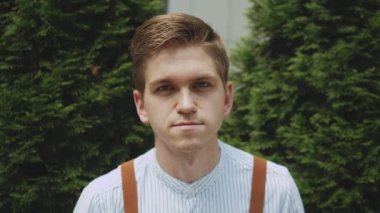 Bir fincan kahveyle bir adamın portresi, şık kıyafetler giymiş biri, ağır çekimde. Adam arka planda iş binasında dikilirken kameraya bakıyor. 4k görüntü