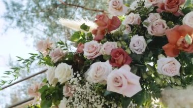 Yeşil yapraklı taze pembe ve sarı güllerden oluşan yakın çekim buketi, düğün kemeri ayrıntıları yavaş çekim. Tam HD görüntüler