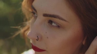 Ağaç kabuğunun yanındaki ormanda poz veren güzel beyaz kadın portresi, tutuş açısı, ağaç dalları arasından görüntü. Yüksek kalite 4k görüntü