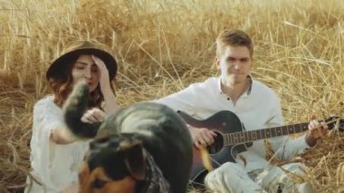 Dikenli alandaki çekici çift yavaş hareket ediyor. Kadın oğlanlara yaslanıyor. Dikenler ellerde. Gitarcı kızı dinleyen adam. 4k görüntü