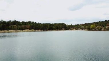 Aerial view of small island with pine trees in the middle of the lake.Unrecognizable people in a boat in the middle of the lake. Close-up shot of island. High quality 4k footage