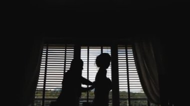 Gelinlik silueti, nedimenin gelinliği giymesine yardım etmesi, mutlu gün, yavaş çekim. Düğün anları. Yüksek kaliteli FullHD görüntüleri.