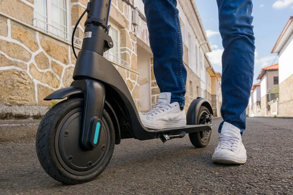 Sokaktaki elektrikli scooter kullanan genç bir adamın bacakları ve ayakları ön taraftan görüldü.